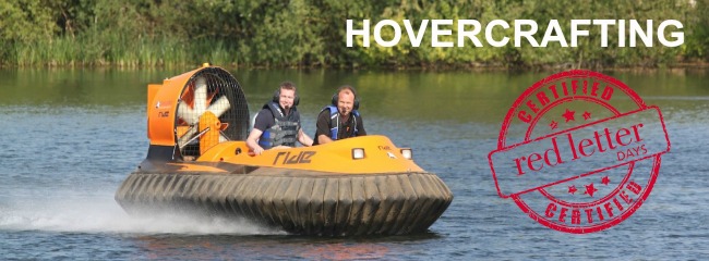 Two men driving a hovercraft over a lake and smiling.