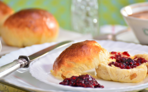 Scones and jam with green wallpaper and cup of tea in the background