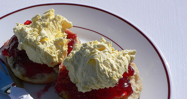 Two scones on a plate with cream and jam