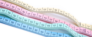 Four tape measures in yellow, pink, green and blue.