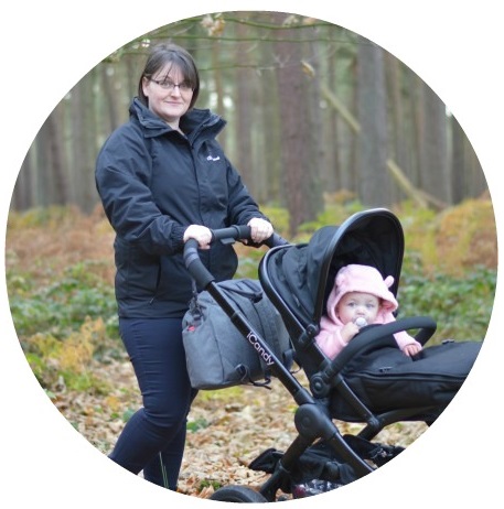Brunette womanin the woods with a baby in a pram
