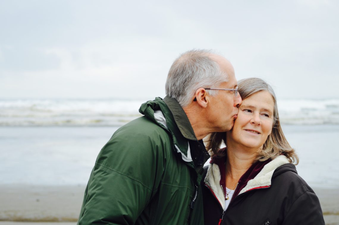 older man kissing his wife on the cheek