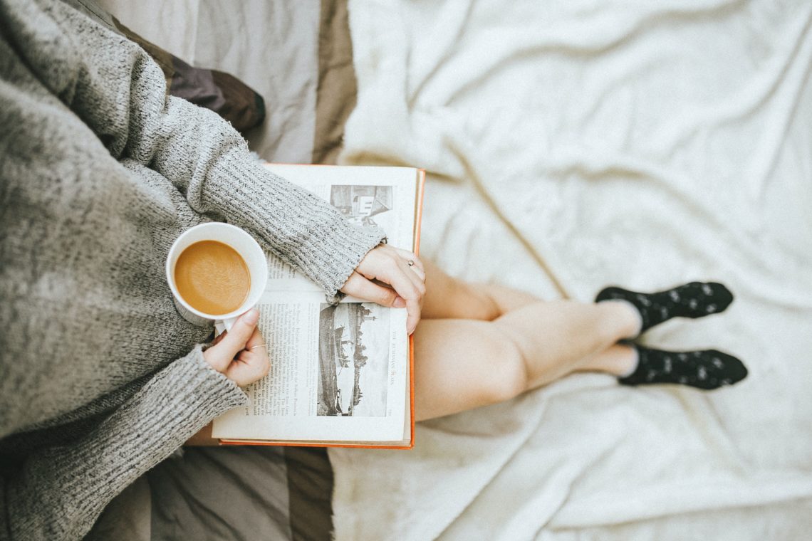 woman reading a book an enjoying a hot drink